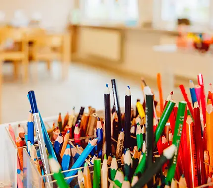 Coloured pencils in a classroom cup